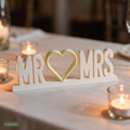 Deko-Schriftzug Mr & Mrs auf Hochzeitstafel umgeben von brennenden Teelichtern, KI-generiert