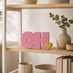 Rosa Deko-Schriftzug „OH.“ aus PLA mit kleinem gelbgrünem Herz auf hellem Hintergrund.